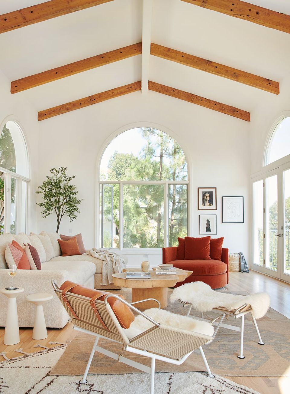 Bright airy living room with exposed wooden beams, rust accent chairs, natural light, and scandinavian-inspired organic modern aesthetic