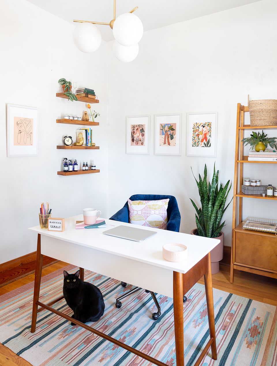 Scandinavian home office with warm wood mid-century desk, floating walnut shelves, white walls, natural light, and minimalist boho accents.