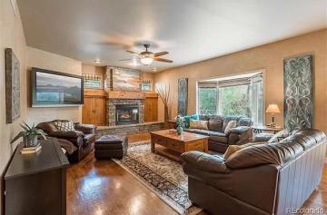 Warm traditional living room with golden-tan walls, dark leather seating, fireplace focal point, and rich wood accents