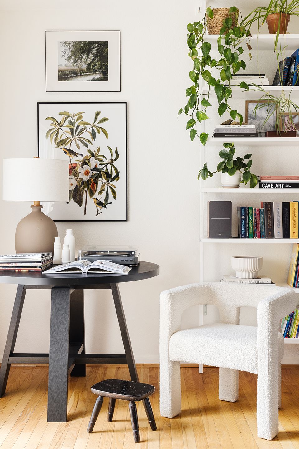 Contemporary workspace with cream armchair, botanical artwork, natural plants, floating shelves, and curated styling in calm, cultured aesthetic.