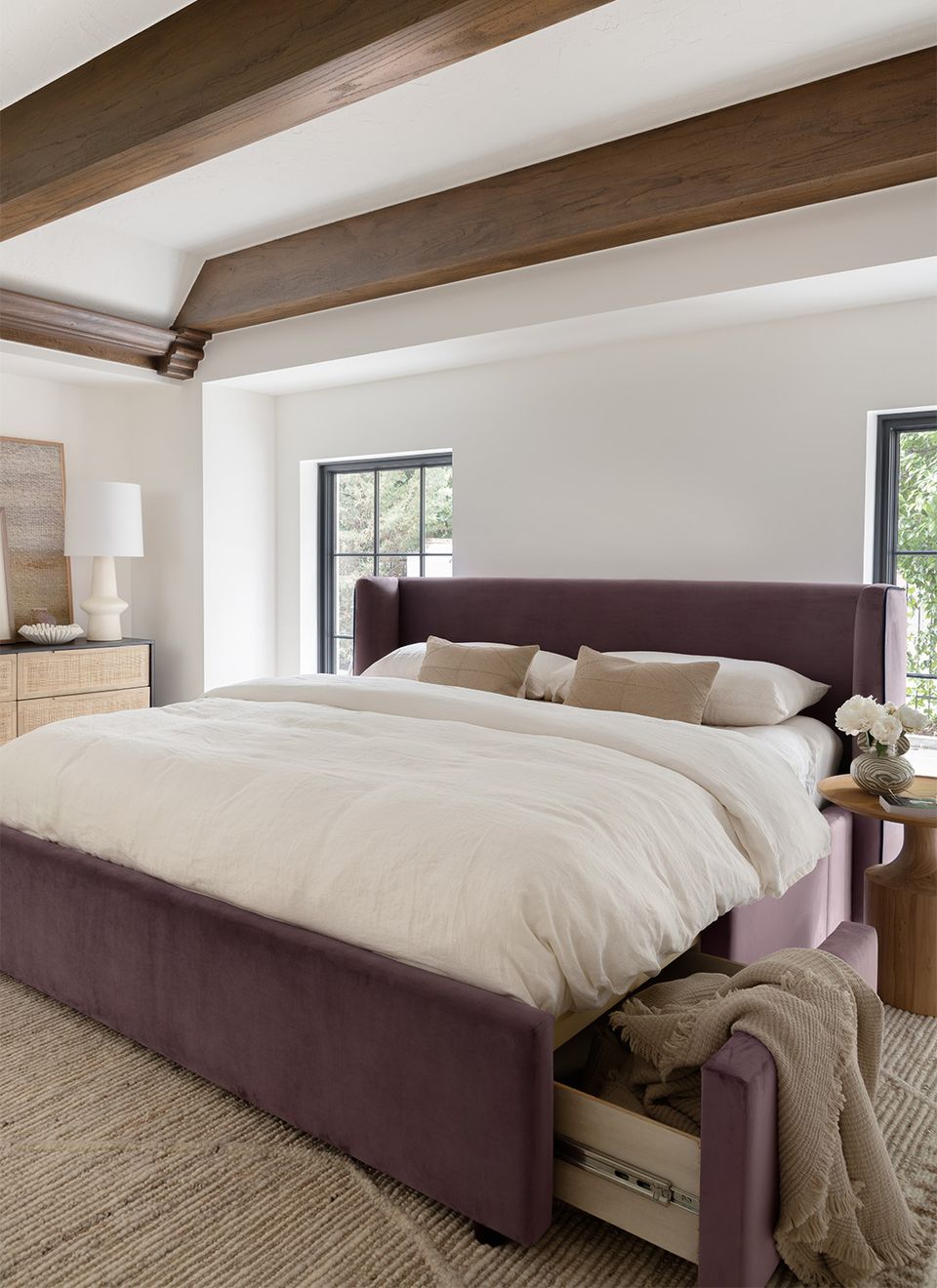 Contemporary storage bed in plum with open drawer, exposed wood ceiling beams, serene neutral palette