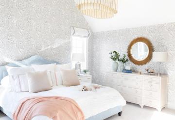 Serene bedroom with soft pink accents, geometric wallpaper, and natural wood elements creating warm, minimalist aesthetic