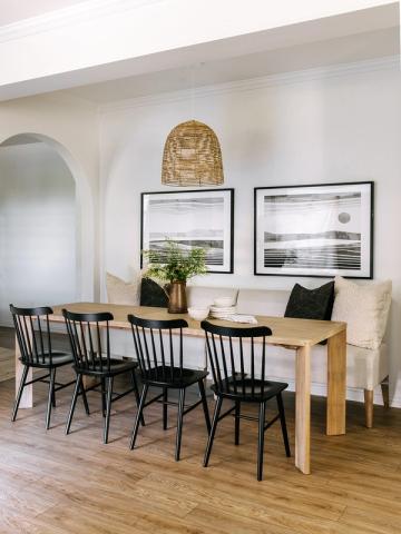 Clean organic modern dining area with natural wood table, black Windsor chairs, and gallery wall art