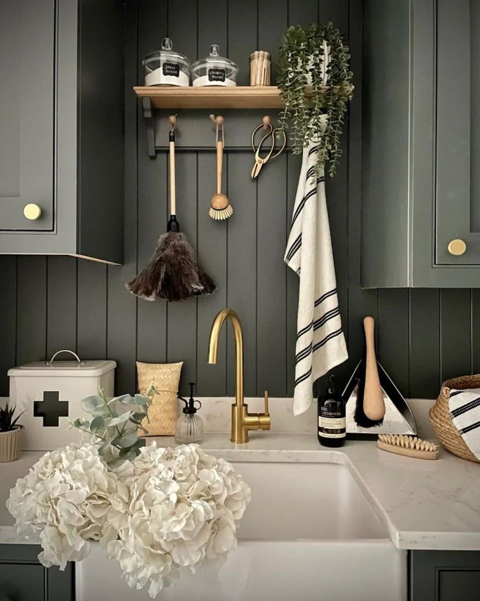 Moody dark gray kitchen with brass accents, white subway tile backsplash, and natural wood shelving displaying kitchen essentials in a sophisticated, organized aesthetic