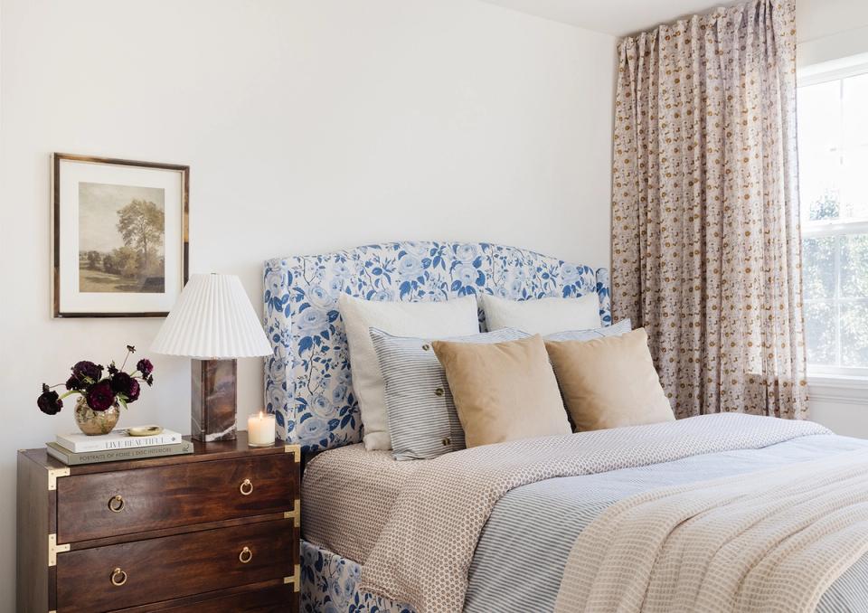 Traditional bedroom featuring blue toile headboard, warm neutral bedding, and warm wood furniture creating classic, elegant comfort.