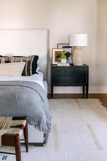 Transitional bedroom blending soft blue bedding, dark nightstand, and warm neutral tones for calm sophistication