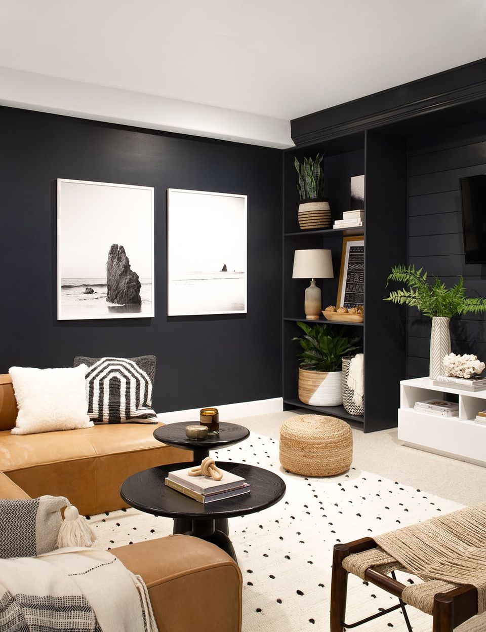 Modern lounge with bold black walls, natural wood, and monochromatic styling.