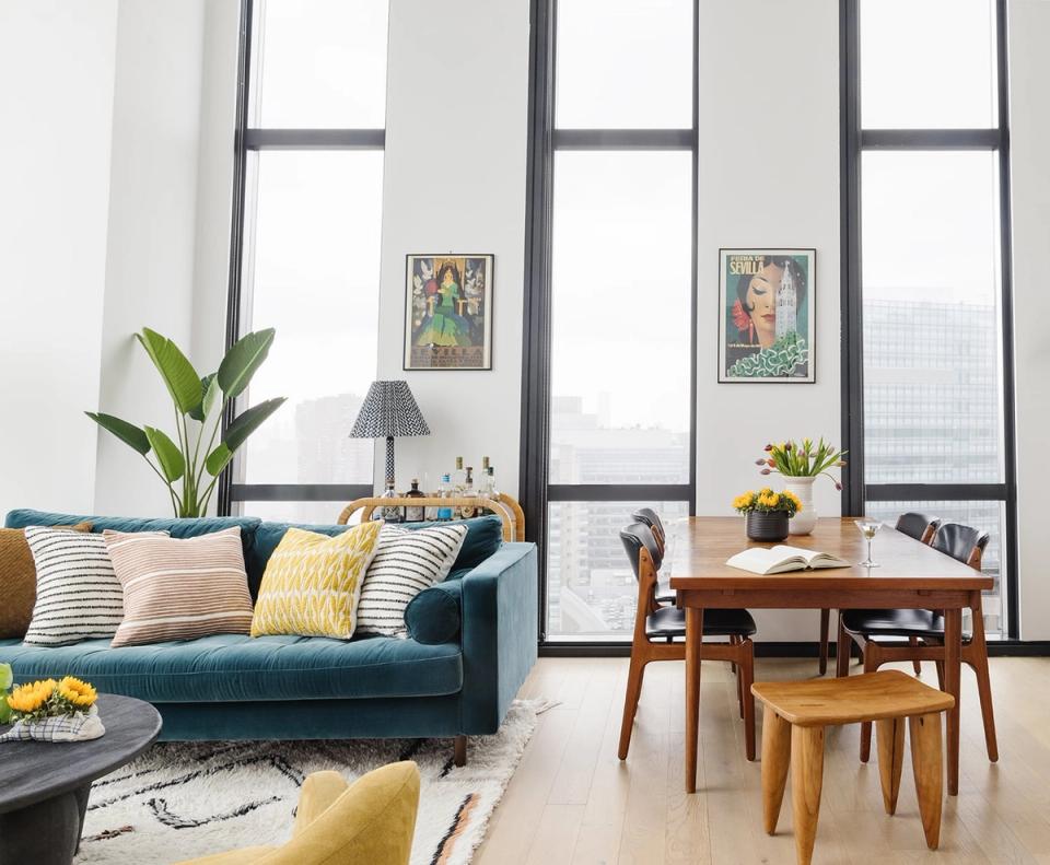Mid-century modern open floor plan with teal sofa, warm wood dining set, and pops of yellow and blue throughout