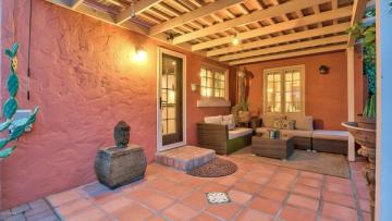 Warm terracotta Spanish colonial patio with earthy tones, wooden pergola, and sculptural accents