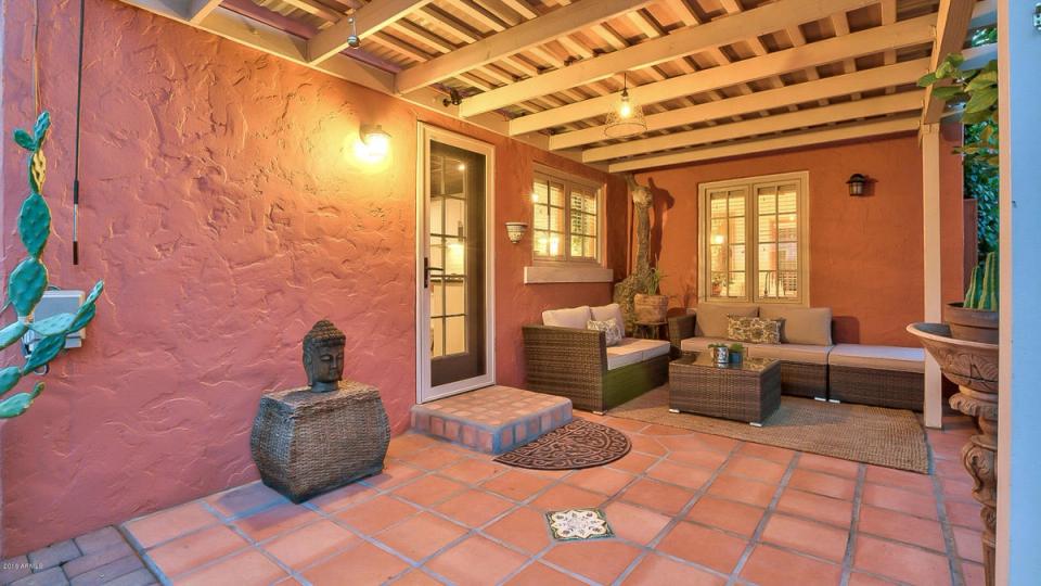 Warm terracotta Spanish colonial patio with earthy tones, wooden pergola, and sculptural accents