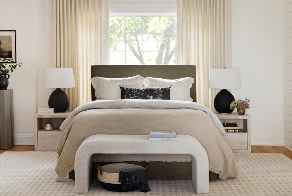 Serene organic modern bedroom with neutral palette, olive upholstered headboard, cream bedding, and curved white bench creating calm, layered aesthetic.