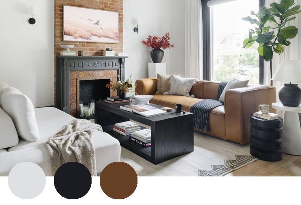 Warm transitional living room blending cognac leather, charcoal, and cream with fireplace accent and mixed wood textures for sophisticated comfort.