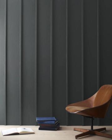 Mid-century modern study nook with dark gray vertical paneling, cognac leather chair, and clean lines emphasizing sophisticated, understated elegance