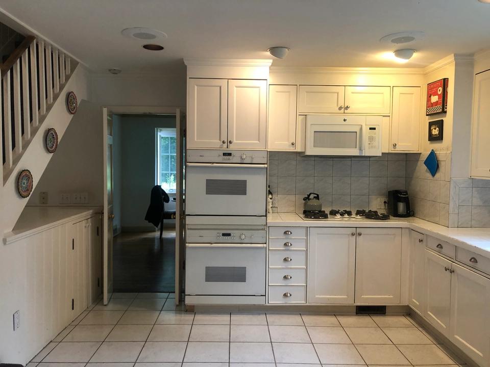 Dated 1980s kitchen with cream cabinets, dual wall ovens, and basic tile flooring