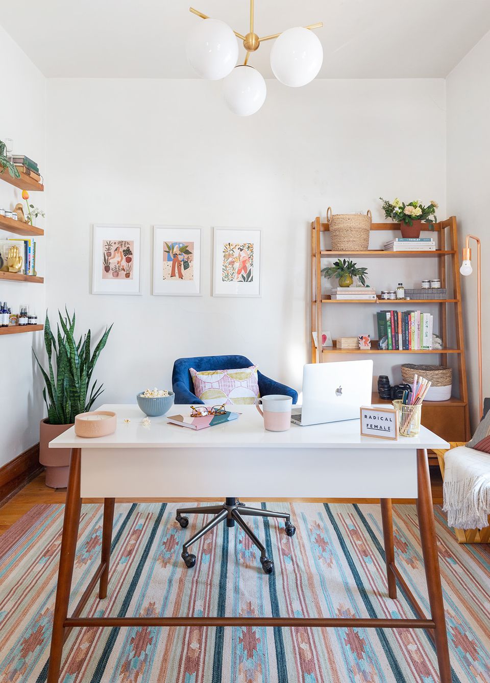 Bright modern workspace with mid-century furniture, navy accents, striped rug, and botanical touches