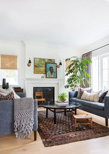 Scandinavian living room with fireplace, dark upholstered sofa, woven accents, and botanical elements in warm neutrals.