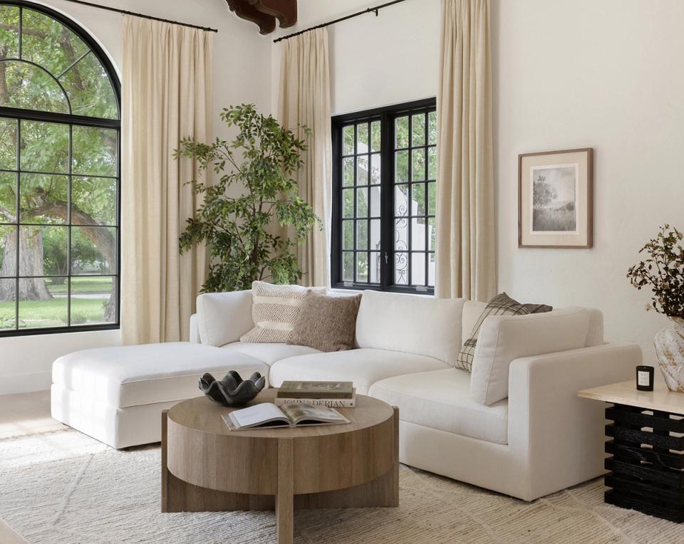 Bright, airy living room with cream sectional, natural wood coffee table, and large windows