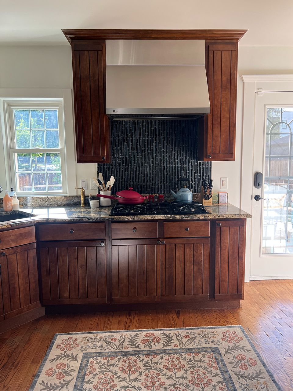 Traditional kitchen with dark wood cabinetry, black tile backsplash, and decorative wood hood detail