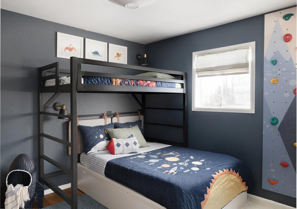 Dark blue bunk room with organized shelving, loft bed, and interactive climbing wall
