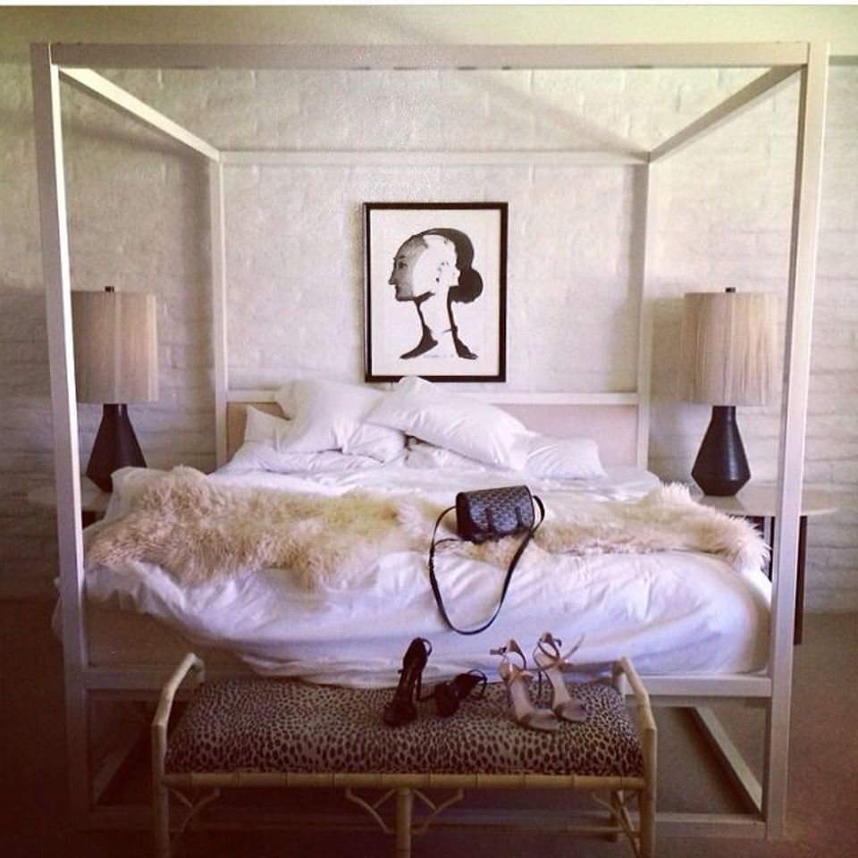 Minimalist bedroom with cream sheepskin throw on canopy bed, black accents, and serene neutral palette