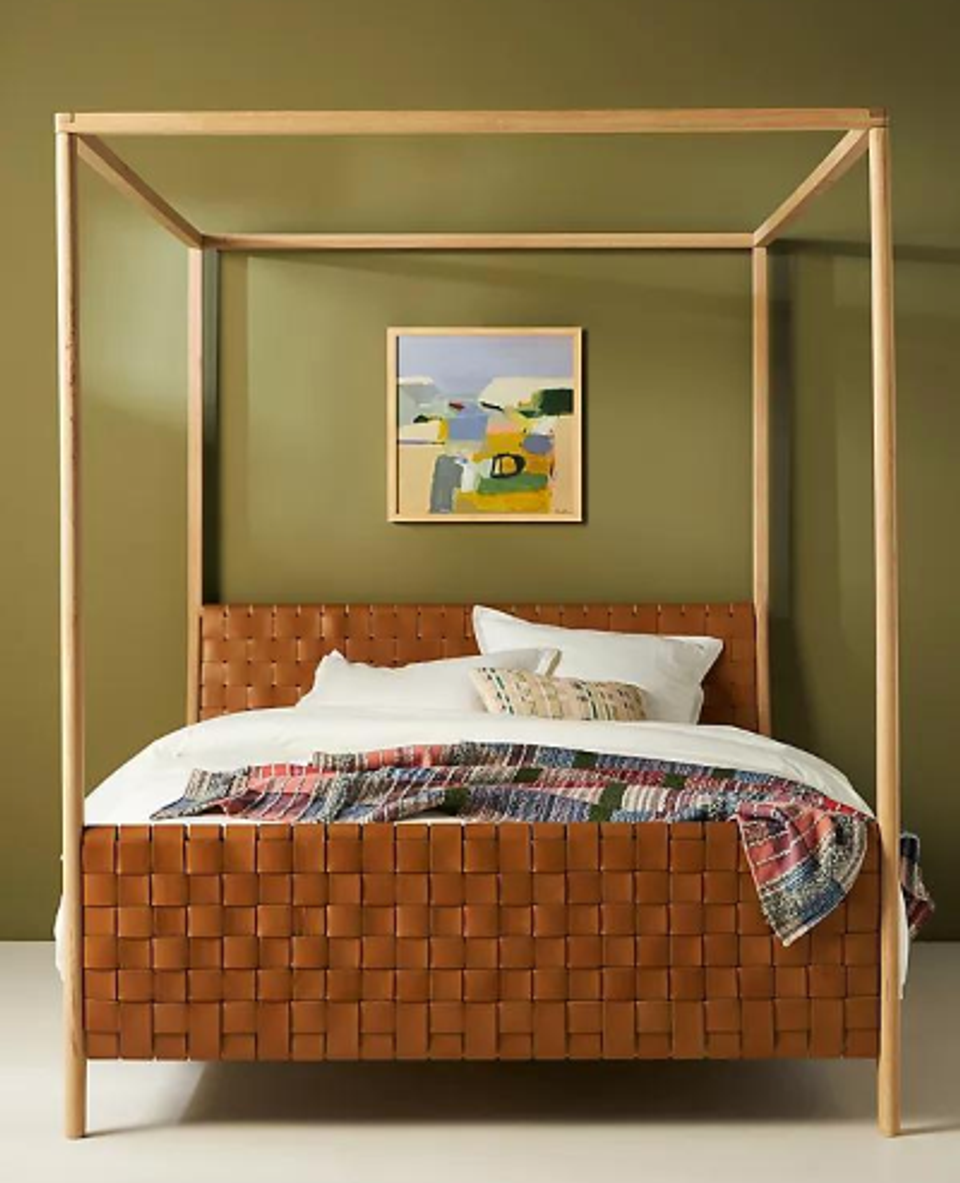 Mid-century modern canopy bed with cognac leather headboard against sage green walls