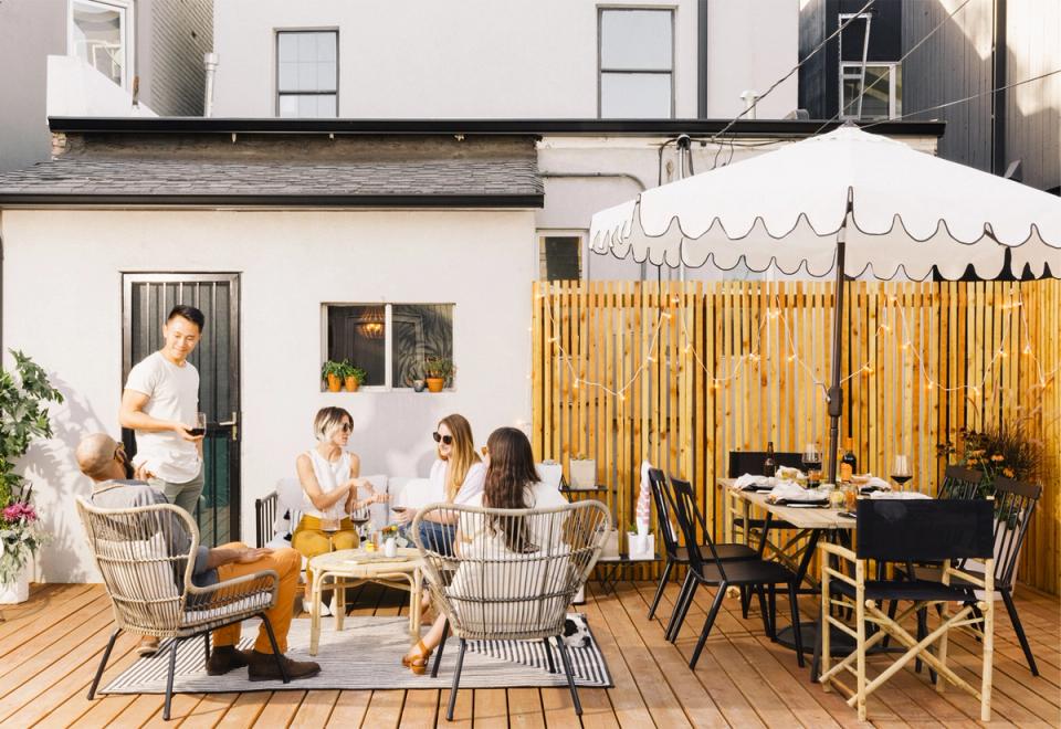 Bright coastal outdoor patio with natural wood tones, woven seating, and modern white canopy creating a relaxed summer entertaining space