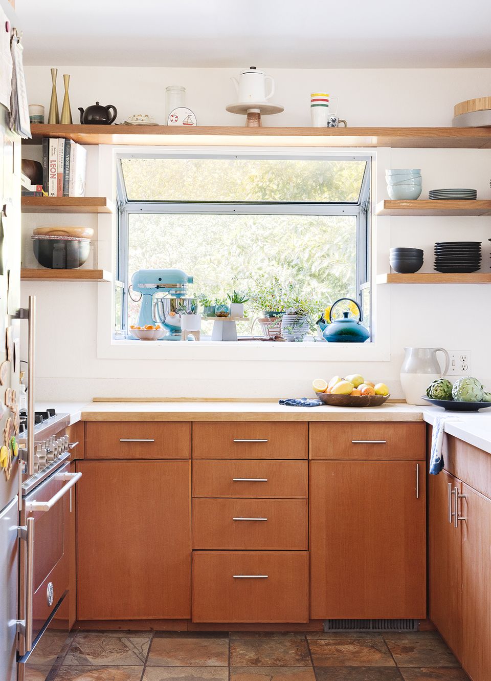 Warm mid-century kitchen featuring natural wood shelves, terracotta cabinetry, and peaceful window-facing design