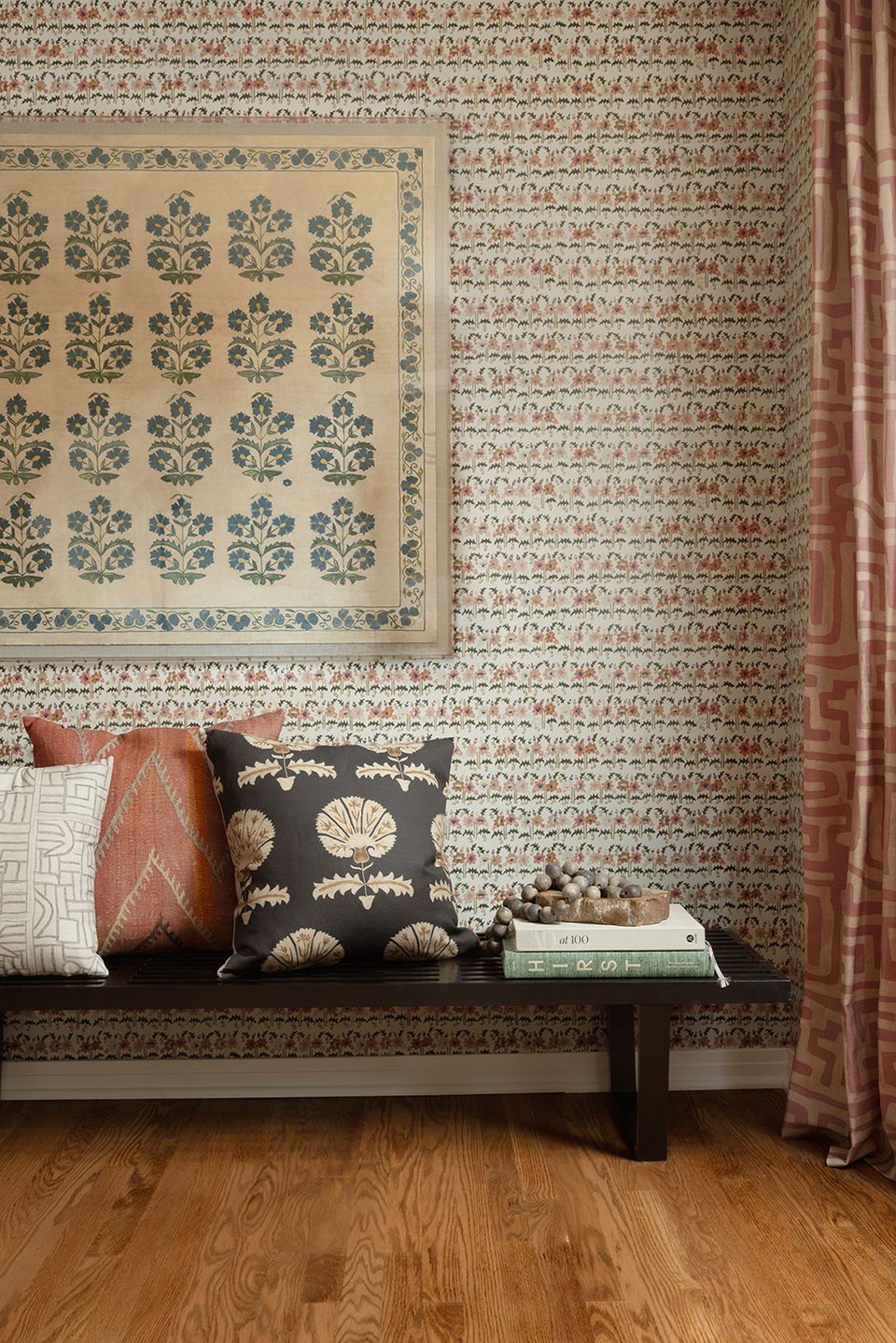 Eclectic entryway with patterned wallpaper, layered textiles in rust and navy tones, and vintage botanical artwork