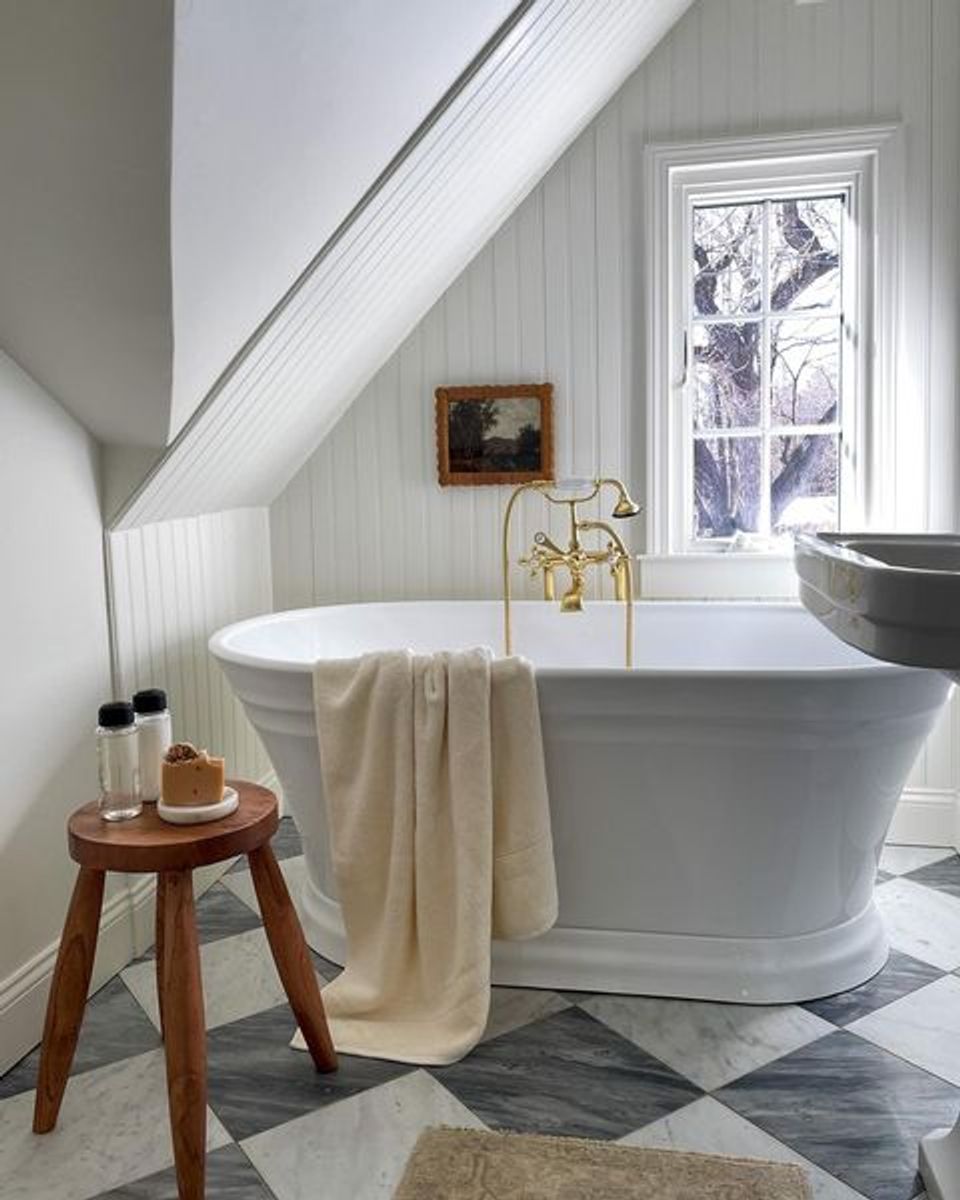 Spa-inspired modern bathroom with soaking tub, wood stool, and coastal color palette