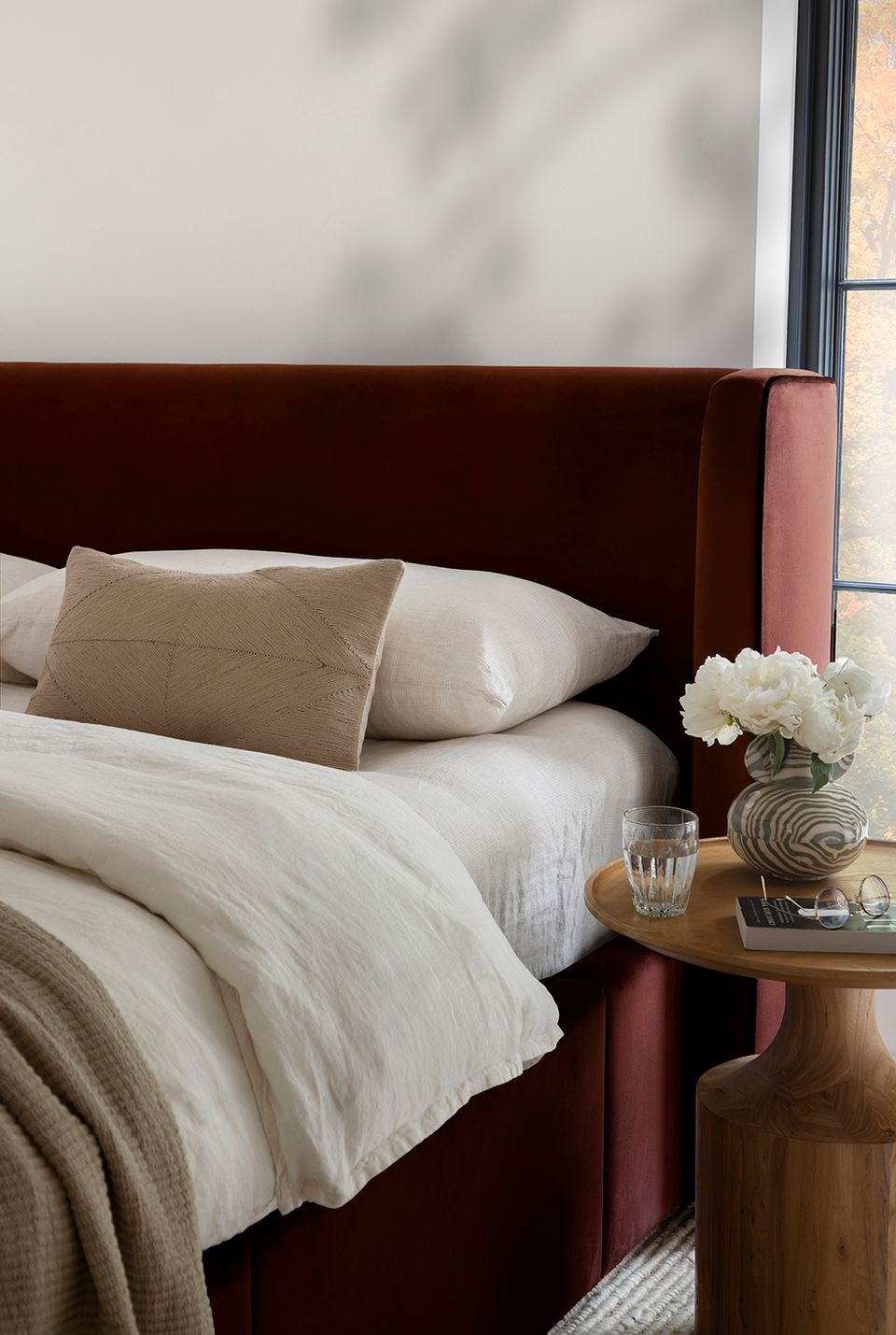 Sophisticated bedroom with burgundy velvet headboard, cream bedding, and warm wood tones