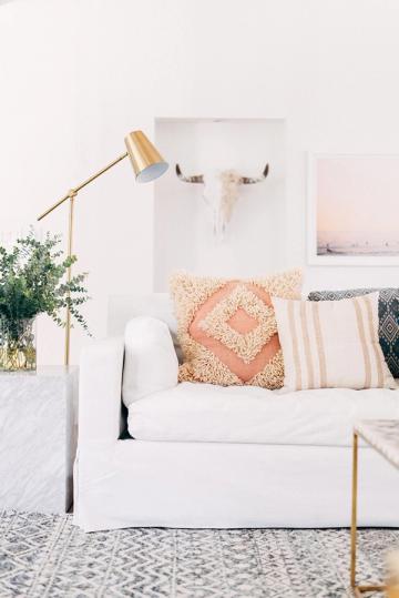 Bright boho-chic bedroom corner with blush and cream palette, brass accents, and layered geometric pillows