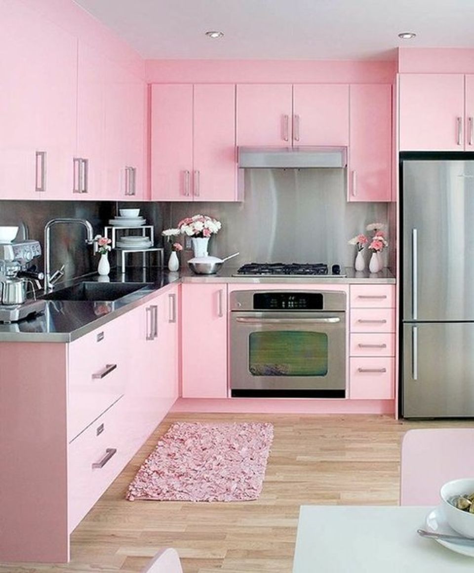 Feminine kitchen in soft pink with stainless steel accents, floral rug, and bright cheerful ambiance