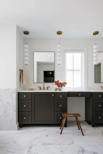 Modern bathroom with dark charcoal vanity, marble flooring, brass fixtures, and crisp white walls creating sophisticated contrast