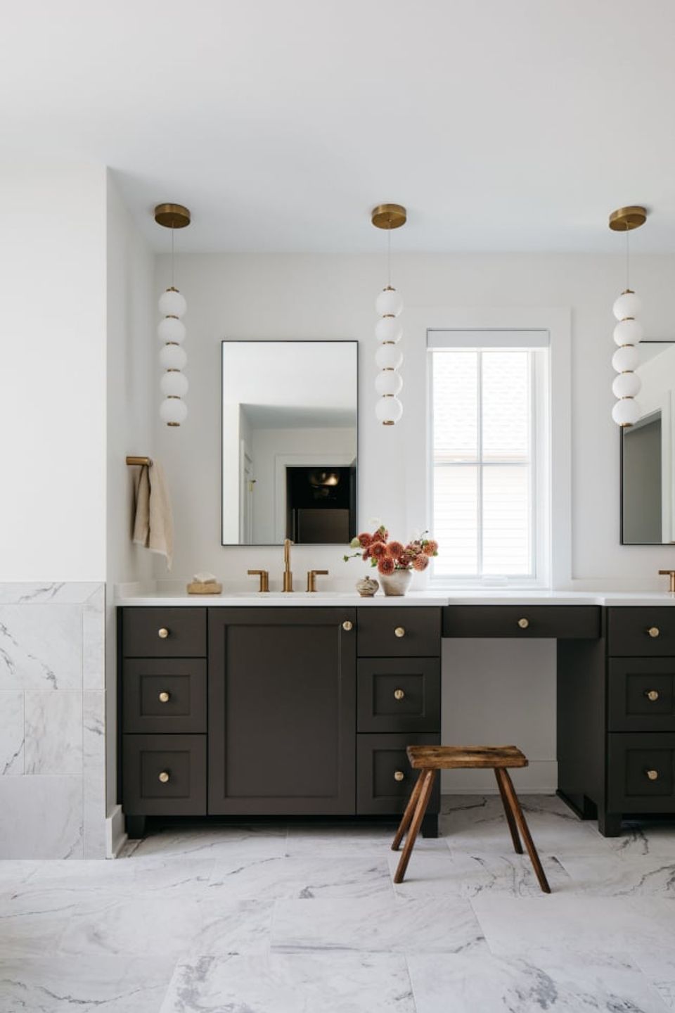 Modern bathroom with dark charcoal vanity, marble flooring, brass fixtures, and crisp white walls creating sophisticated contrast