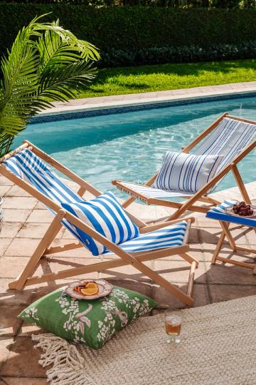 Vintage-inspired deck chairs with striped cushions beside turquoise pool, tropical plants