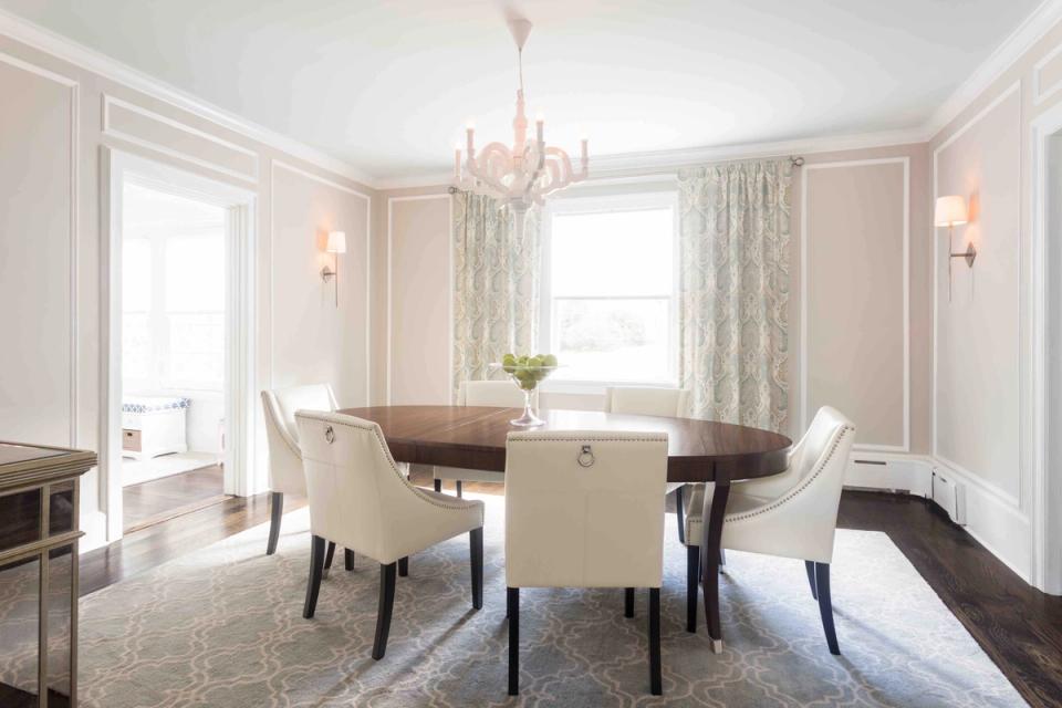 Elegant traditional dining room with blush paneling, round table, and crystal chandelier