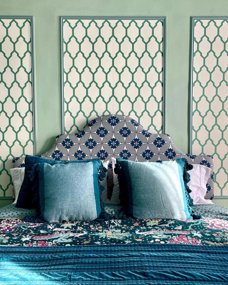 Cottage-inspired bedroom with pale green patterned accent panels, blue and floral bedding