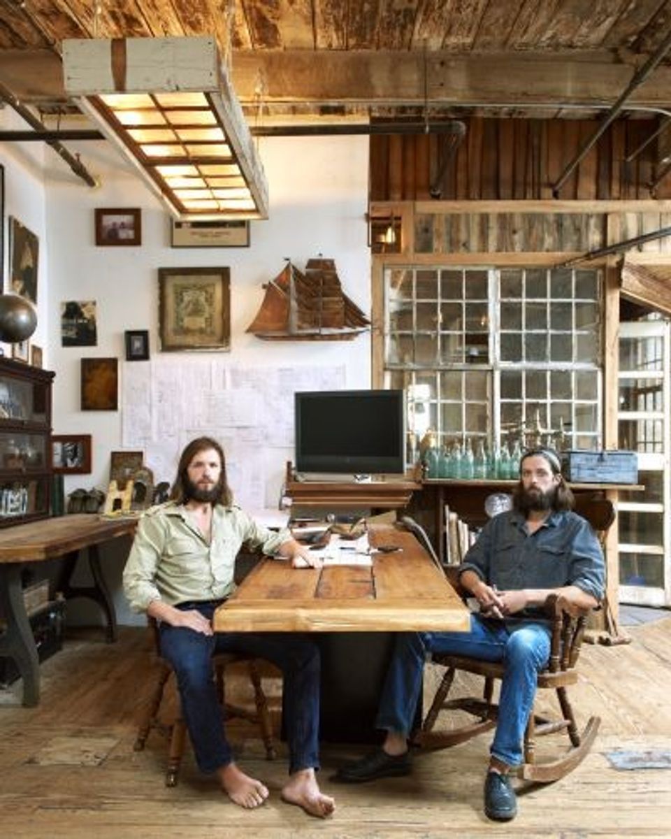 Industrial workspace with warm wood ceiling panels and integrated linear lighting fixtures in rustic setting