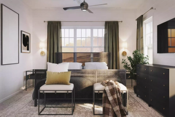 Contemporary bedroom with black furniture, olive curtains, and warm brass pendant lighting
