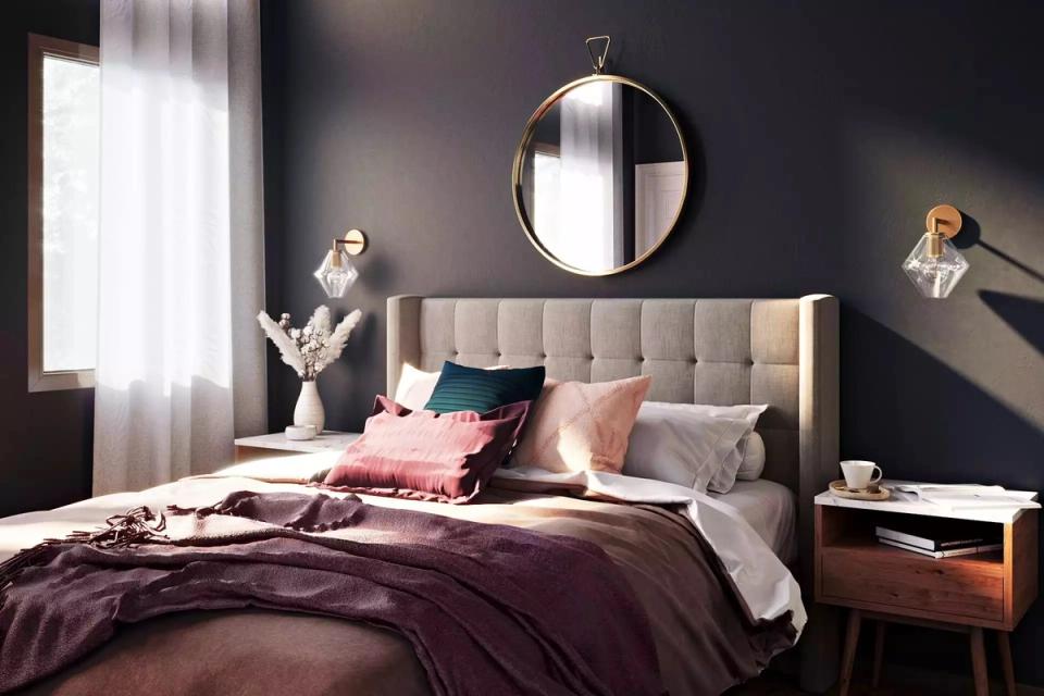 Moody dark bedroom with blush upholstered headboard, jewel-tone bedding, and sophisticated ambiance
