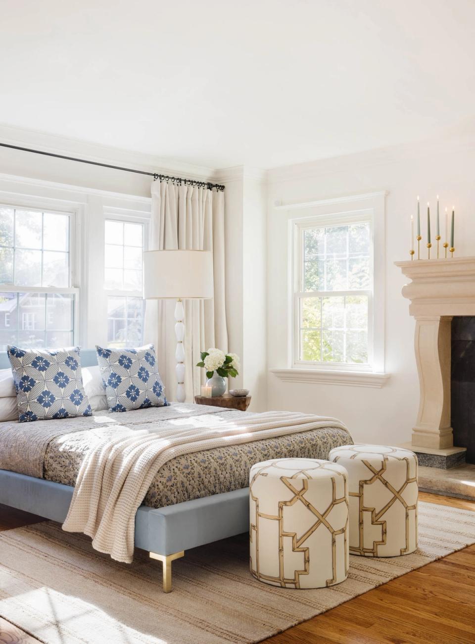 Bright preppy bedroom with blue and white geometric pillows, neutral bedding, and minimalist fireplace accent