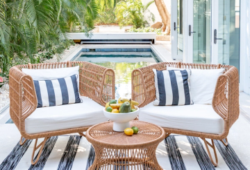 Coastal poolside seating with woven rattan chairs, navy striped pillows, and natural materials creating a breezy, nautical retreat.