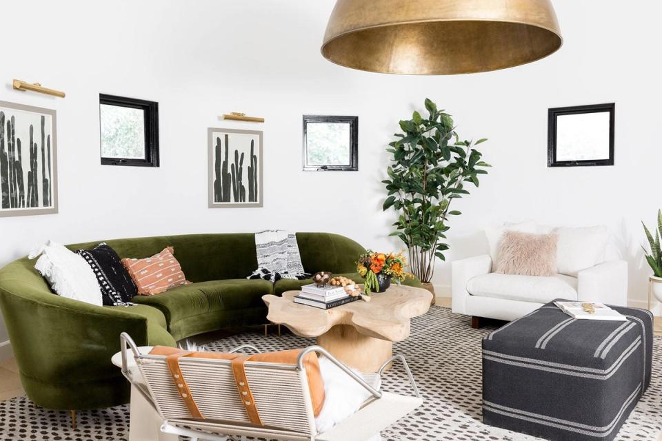Modern living room with olive green sofa, brass pendant light, and gallery wall creating focal point emphasis through contrasting frames and artwork.