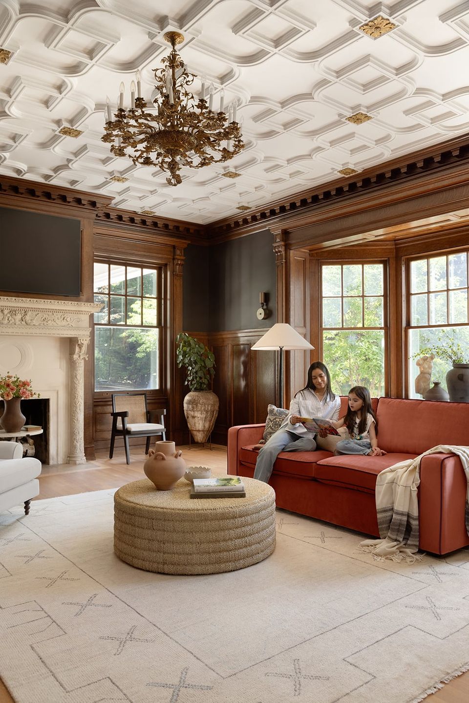 Classic traditional living room with warm wood paneling, brass chandelier, and terracotta sofa