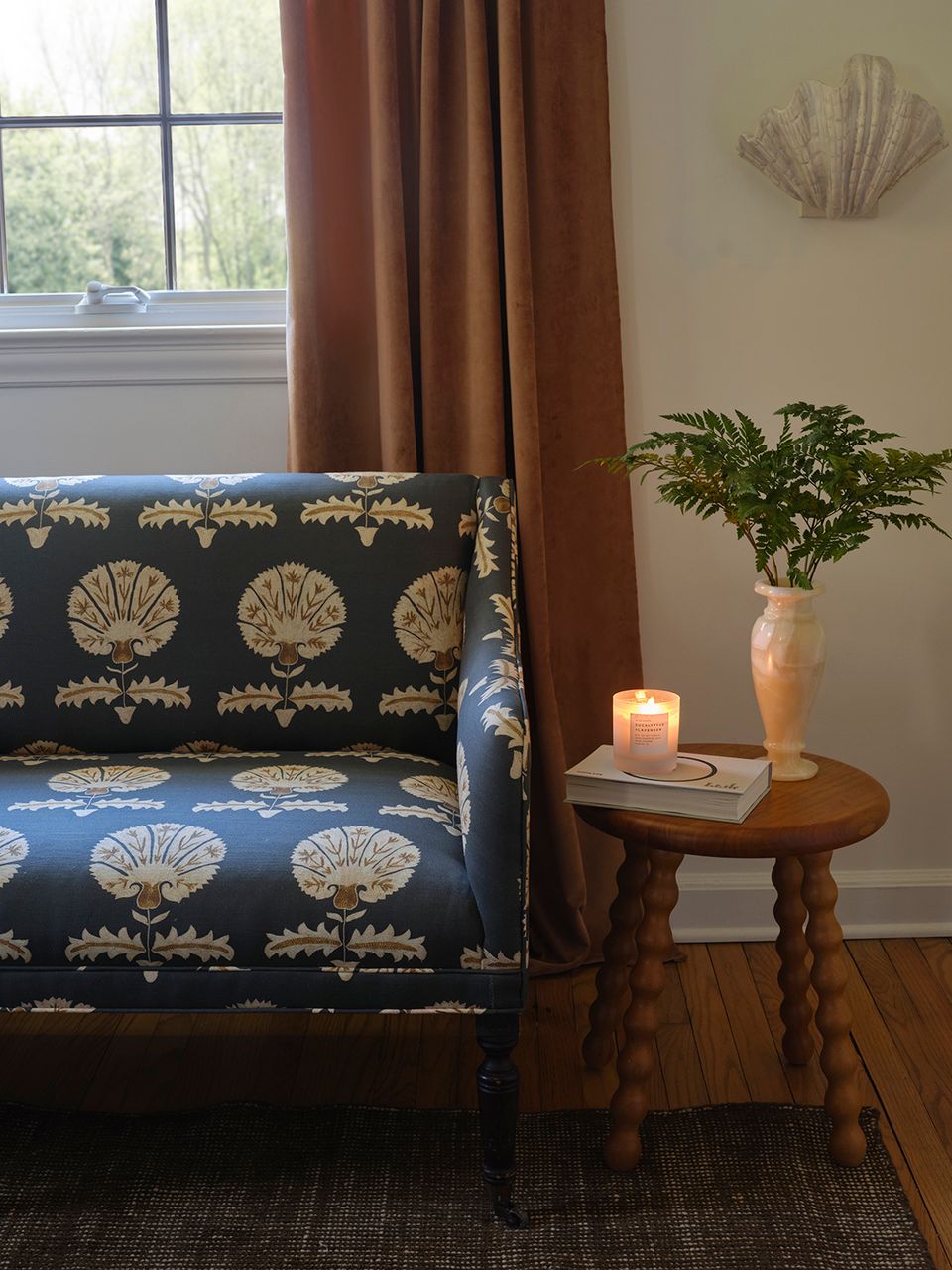 Eclectic sitting area with navy shell-patterned chair, terracotta vase, and warm brown drapery