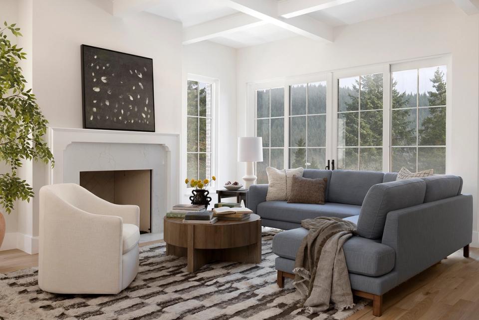 Bright, airy living room with cream and charcoal palette, fireplace, large windows, and cozy mid-century furniture arrangement.