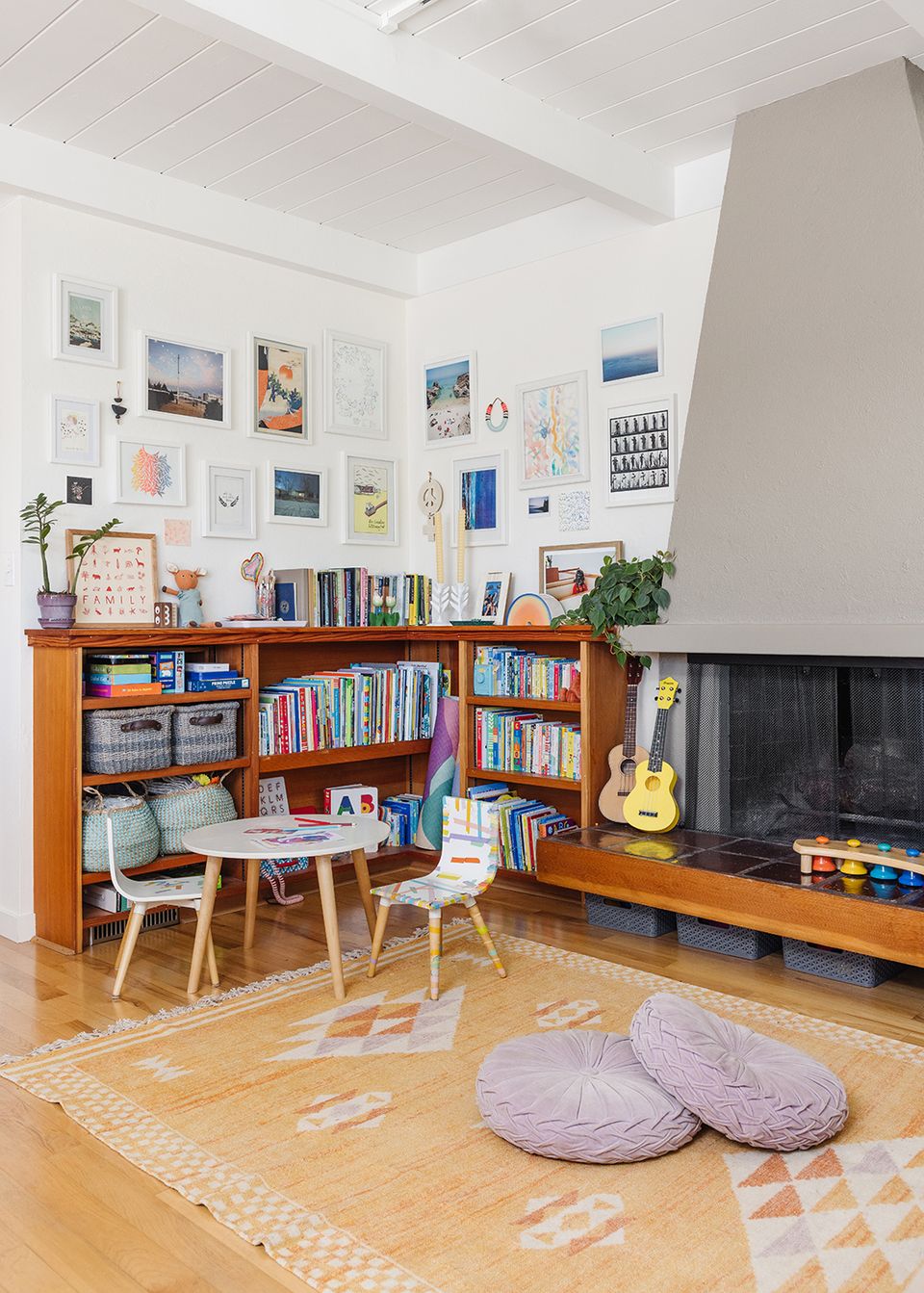 Eclectic family room blending mid-century wood cabinetry, gallery wall art, and warm wood flooring with playful, creative energy
