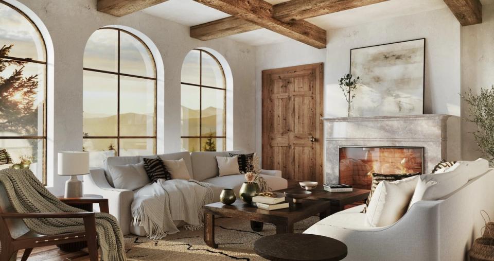 Bright Mediterranean living room with arched windows, exposed wooden beams, warm terracotta tones, and a cozy fireplace