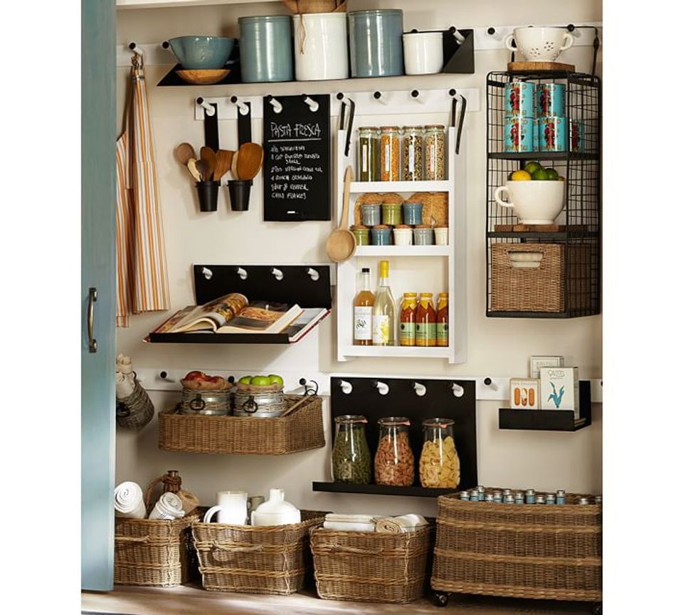 Organized kitchen wall system mixing open shelving, woven baskets, and pegboard in neutral tones