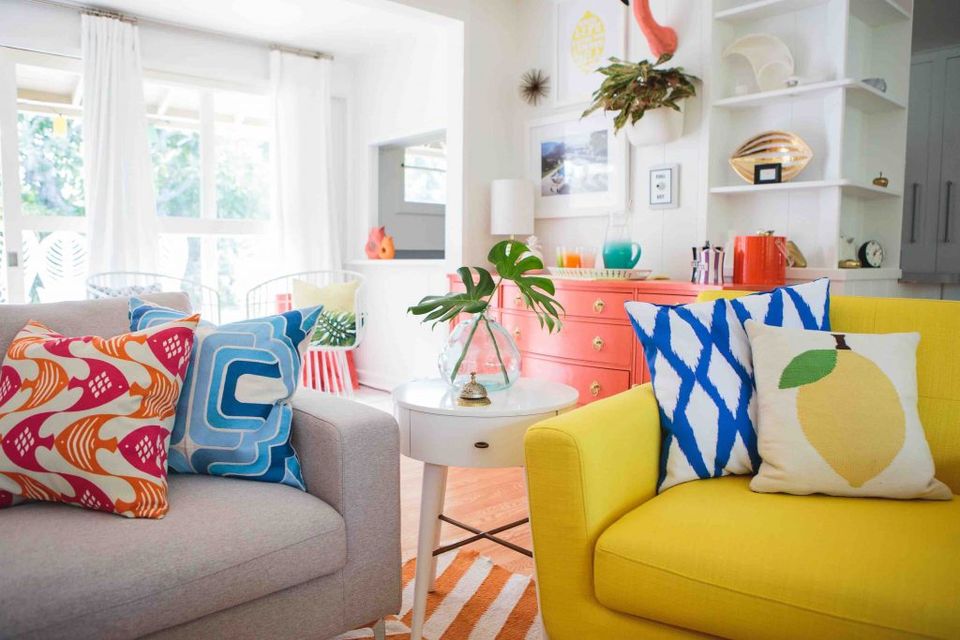 Vibrant eclectic family room with jewel tones, bold geometric pillows, playful color mixing, and energetic modern style.
